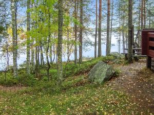 SavonrantaにあるHoliday Home 2233 by Interhomeの湖畔の森のベンチと岩