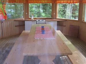 a large wooden table in a kitchen with windows at Holiday Home Varvali by Interhome in Lahdenkylä