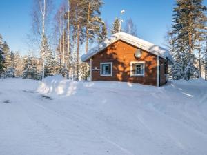 a log cabin in the snow with trees in the background at Holiday Home Aamunsarastus by Interhome in Savonranta