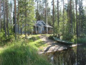 ein kleines Haus im Wald mit einem Boot im Wasser in der Unterkunft Holiday Home Käpälämäki by Interhome in Lahdenkylä