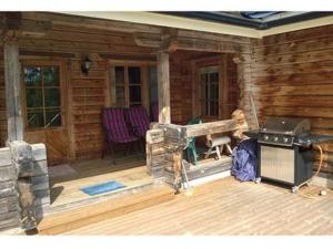 a porch of a log cabin with a grill at Holiday Home 5650 by Interhome in Koskenpää