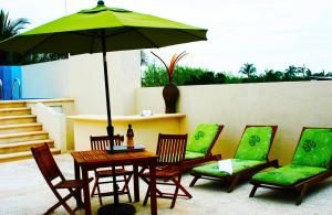 a table and chairs with a green umbrella on a patio at Hotel Chapul Inn in Acapulco