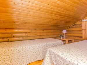 two beds in a room with wooden walls at Holiday Home Karhulinna by Interhome in Miehoila