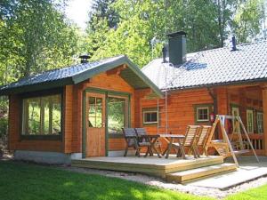 a wooden cabin with a table and chairs on a deck at Holiday Home Rantatupa by Interhome in Hyyrylä