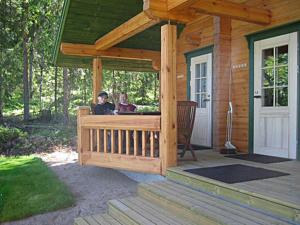 two people sitting on the porch of a wooden cabin at Holiday Home Pikkutupa by Interhome in Hyyrylä