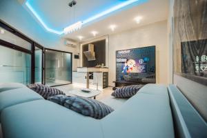 ein Wohnzimmer mit einem Sofa und einem TV in der Unterkunft H & V Residence - Diamond Bungalow Apartment in Arad