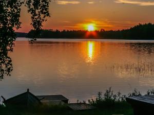 a sunset on a lake with the sun setting at Holiday Home Ettone by Interhome in Lipinlahti