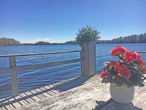 a wooden dock with flowers in a vase next to a fence at Holiday Home Suviranta by Interhome in Syvärinpää