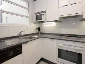 eine weiße Küche mit einer Spüle und einer Mikrowelle in der Unterkunft Apartment Vila Olimpica Sant Marti - Sardenya by Interhome in Barcelona