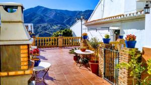 a balcony with tables and potted plants and mountains at Casa Rural María in Carratraca