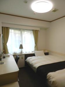 um quarto de hotel com duas camas e uma janela em Check In Matsuyama em Matsuyama