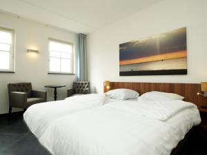 ColijnsplaatにあるHoliday Home Ganuenta-2 by Interhomeの白い大型ベッドと椅子が備わるホテルルームです。