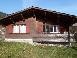 a small wooden house with red shutters on it at Apartment Bodehus by Interhome in Adelboden