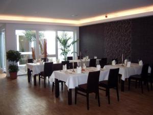 a dining room with white tables and black chairs at Akzent Hotel Deutsche Eiche in Uelzen
