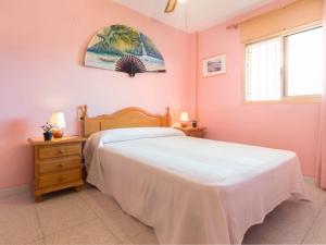 カンブリルスにあるApartment Els Espigons by Interhomeのピンクの壁のベッドルーム(ベッド1台、窓付)