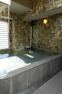Habitación con paredes de piedra y bañera de hidromasaje en un edificio en Check In Matsuyama en Matsuyama