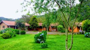 a house in a yard with a green lawn at Recanto da Natureza- Chalé in Gonçalves +42 photos