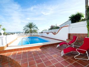 una piscina en un patio con 2 sillas rojas y una piscina en Villa Casa Sanne by Interhome, en Calpe