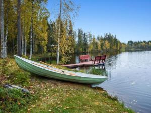 ein Boot und zwei Stühle am Ufer eines Sees in der Unterkunft Holiday Home Mykkylä by Interhome in Niemi