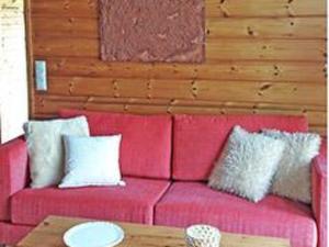 - un canapé rouge avec des oreillers et une table dans la chambre dans l'établissement Holiday Home Alahuone by Interhome, à Pätiälä
