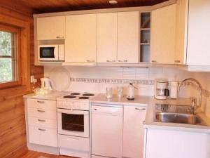 a white kitchen with white cabinets and a sink at Holiday Home Alahuone by Interhome in Pätiälä