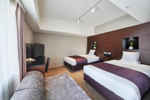 um quarto de hotel com duas camas e uma televisão em HOTEL MYSTAYS Shimizu em Shizuoka