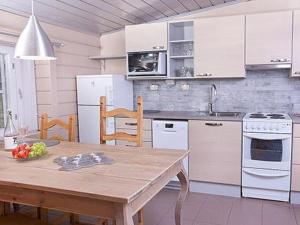 a kitchen with a wooden table and a kitchen with white appliances at Holiday Home Peltotupa by Interhome in Pätiälä