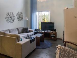 ein Wohnzimmer mit einem Sofa und einem TV in der Unterkunft Holiday Home Vuokatinlampi 7 b by Interhome in Lahdenperä