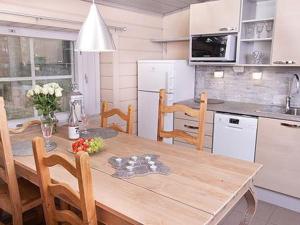 uma cozinha com uma mesa de madeira com cadeiras e uma cozinha com em Holiday Home Peltotupa by Interhome em Pätiälä