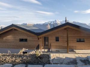 a house with a roof with mountains in the background at Apartment Huwetz 3 1-2 Zimmerwohnung by Interhome in Bettmeralp