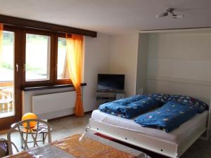 1 dormitorio con cama, mesa y TV en Apartment Silberdistel by Interhome en Saas-Grund
