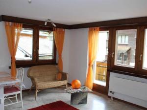 sala de estar con sofá, silla y ventanas en Apartment Silberdistel by Interhome en Saas-Grund