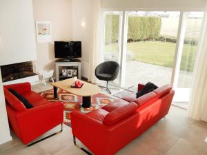 ノールトウェイクにあるHoliday Home de Witte Raaf-2 by Interhomeのリビングルーム(赤い椅子2脚、テーブル付)