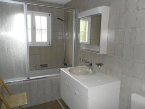een witte badkamer met een wastafel en een spiegel bij Apartment Kronenplatz 6 # 2 by Interhome in Lenk