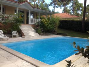 a swimming pool in front of a house at Holiday Home Eden Parc in Lacanau-Océan