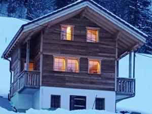 a log cabin with its lights on in the snow at Apartment Chalet Wäschhüsi by Interhome in Adelboden