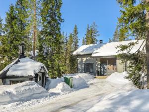 a house covered in snow next to a dirt road at Holiday Home Aihki a by Interhome in Syöte