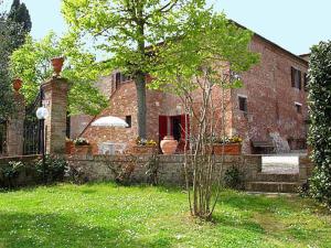 una casa de ladrillo con un árbol en un patio en B&B Le Logge Di Sopra, en Asciano
