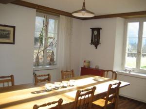 una sala da pranzo con tavolo, sedie e finestre di Apartment Villa Alpenblick Wolfenschiessen by Interhome a Wolfenschiessen