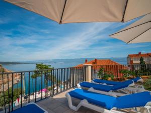 a balcony with blue chairs and an umbrella at Villa Vali 1 by Interhome in Vrbnik