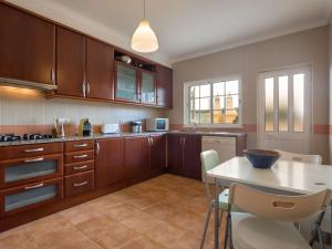 a kitchen with wooden cabinets and a table with chairs at Holiday Home Grand Beach Hit by Interhome in Pêra
