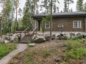 una cabaña de madera en el bosque con escaleras y rocas en Holiday Home Apilan rauha by Interhome, en Kerttee