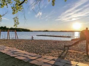 a person sitting on a bench next to the water at Holiday Home Hästöskata a by Interhome in Kruunupyy