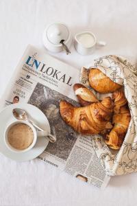 een krant met een bord croissants en een kopje koffie bij Gaestehaus Schaefersruh in Haffkrug