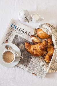 a newspaper with a plate of croissants and a cup of coffee at Gaestehaus Schaefersruh in Haffkrug