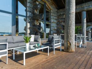 eine Terrasse mit einem Sofa und Stühlen auf einer Holzterrasse in der Unterkunft Holiday Home Villa pärla by Interhome in Myllykangas