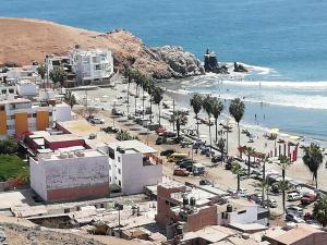 a beach with buildings and palm trees and the ocean at Casa Blue Hill Beach in Cerro Azul