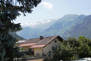 a house with a roof with mountains in the background at Mountain Motel in Kaprun