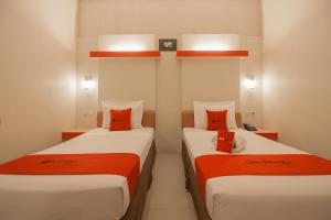 2 camas en una habitación con naranja y blanco en RedDoorz Plus near Kampung Gajah 3, en Bandung