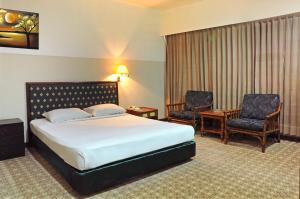 Hotel Banyuwangi Sintera في جاكرتا: غرفه فندقيه بسرير وكرسيين